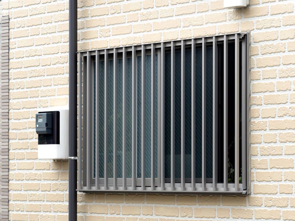 A Brick Building With a Window With Bars on It — Whitsunday Screens & Grilles In Proserpine, QLD