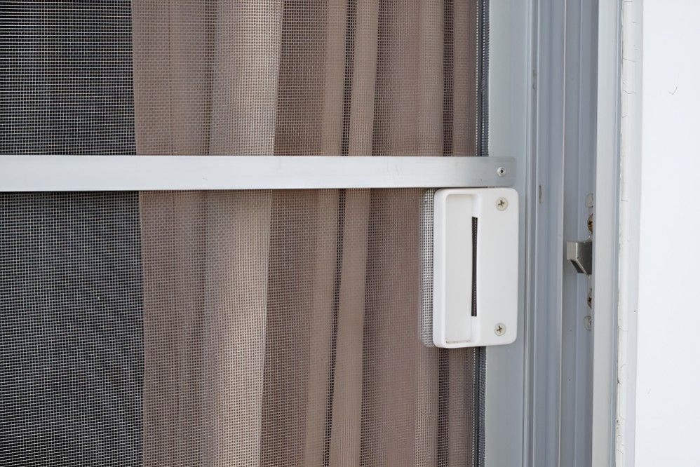 A Close Up of a Sliding Glass Door With a White Handle — Whitsunday Screens & Grilles In Airlie Beach, QLD