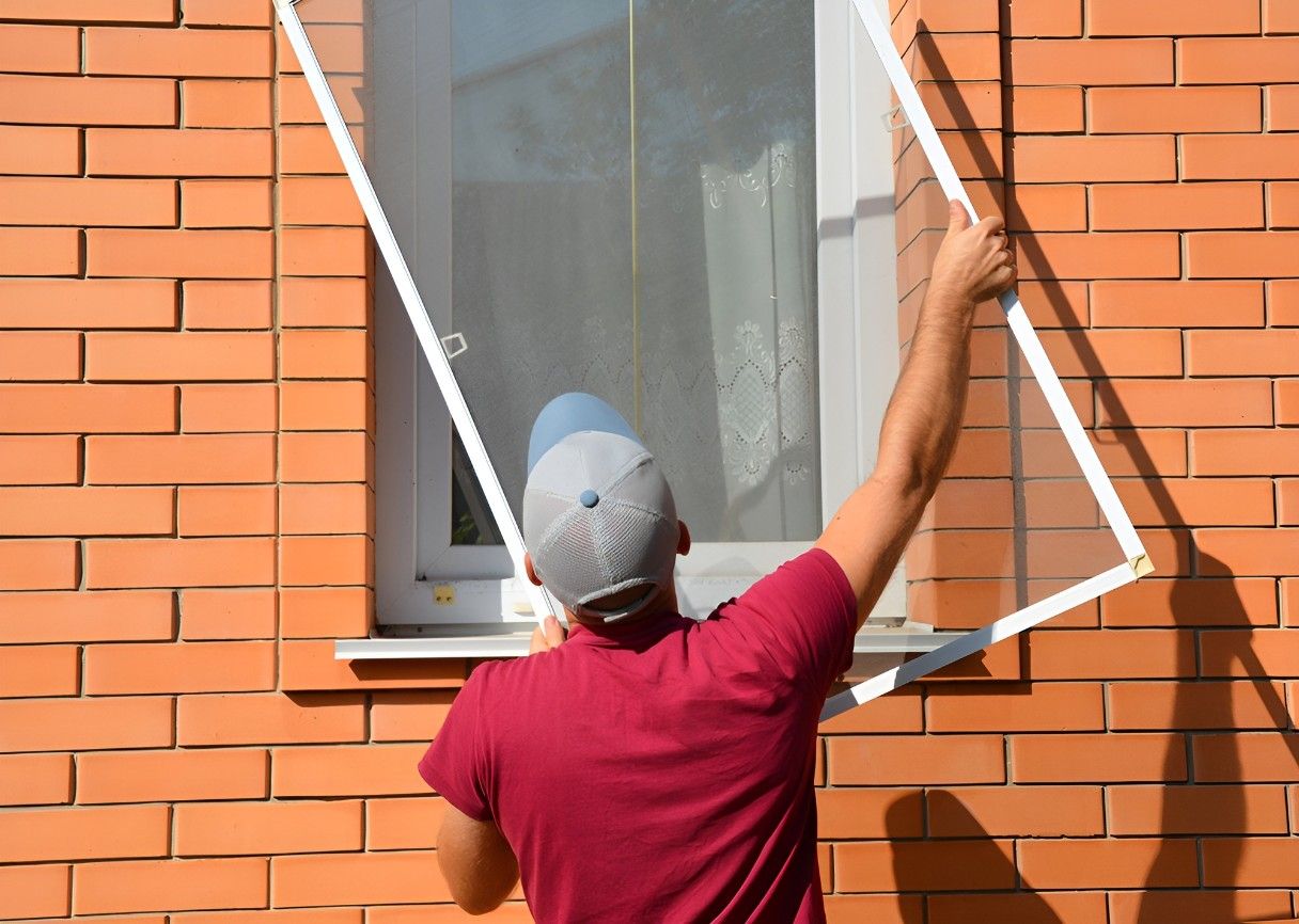 A Man is Installing a Mosquito Net on a Window — Whitsunday Screens & Grilles In Proserpine, QLD