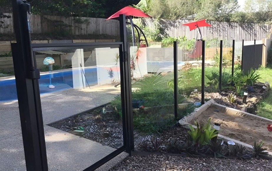 A Glass Fence Surrounds a Swimming Pool in a Backyard — Whitsunday Screens & Grilles In Proserpine, QLD