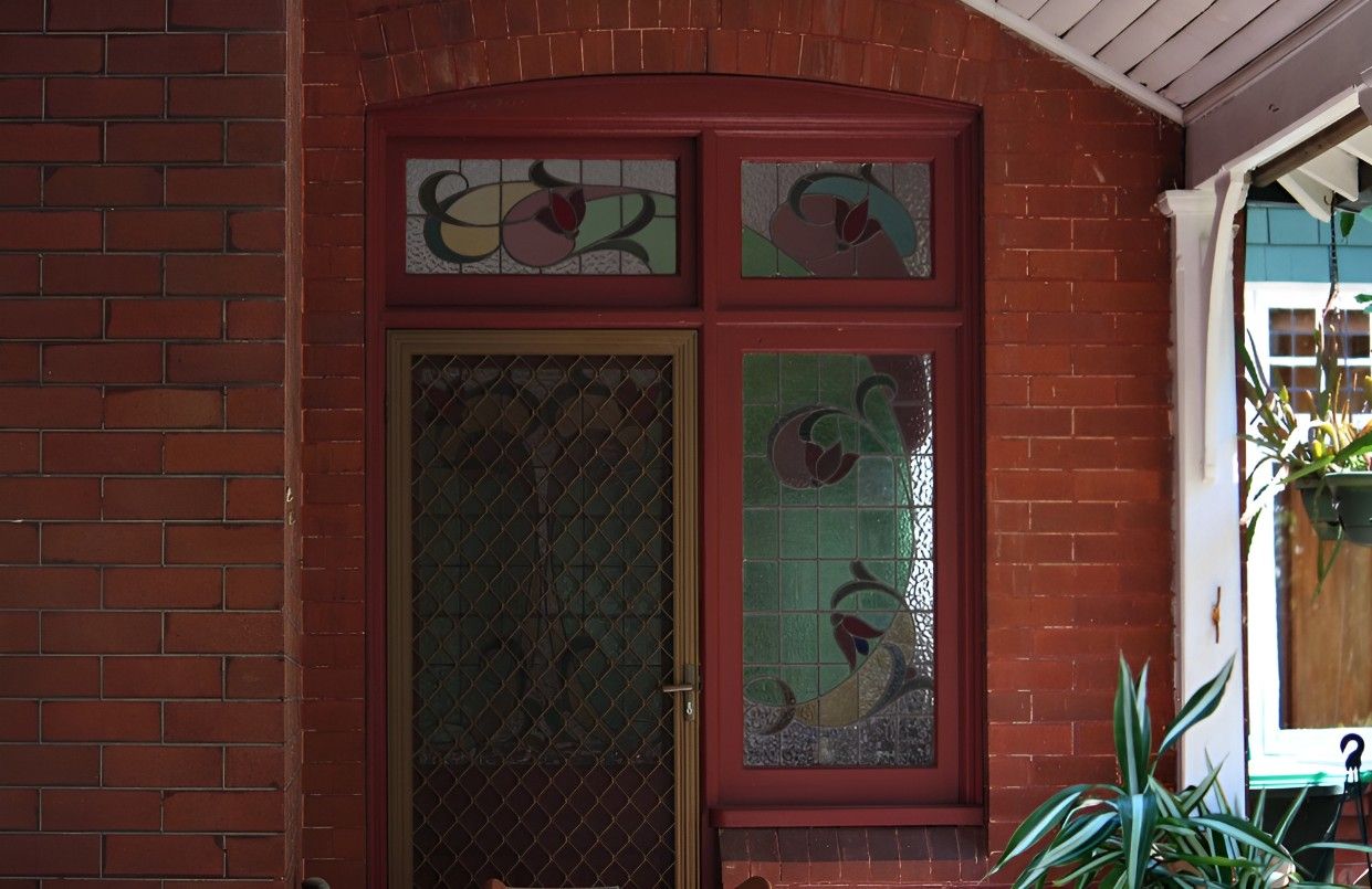 A Red Brick Building With a Stained Glass Window — Whitsunday Screens & Grilles In Proserpine, QLD