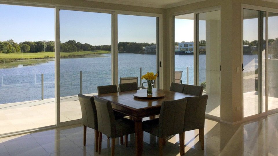 A Dining Room With a Table and Chairs Overlooking a Lake — Whitsunday Screens & Grilles In Airlie Beach, QLD