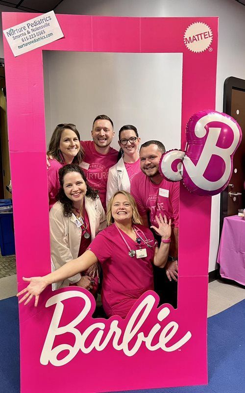 A group of six people posing inside a bright pink
