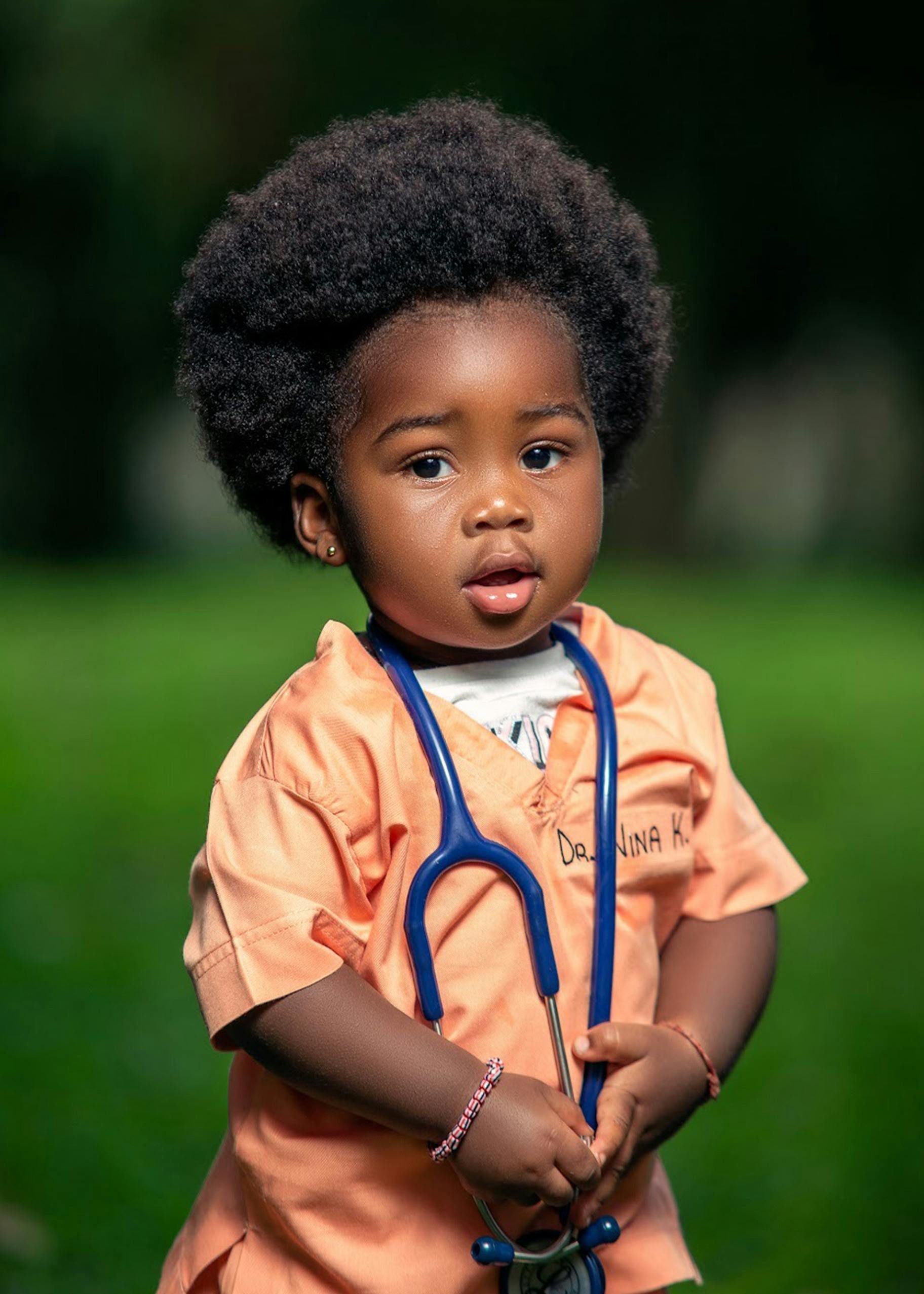 A young child in a park with a stethoscope around their neck.