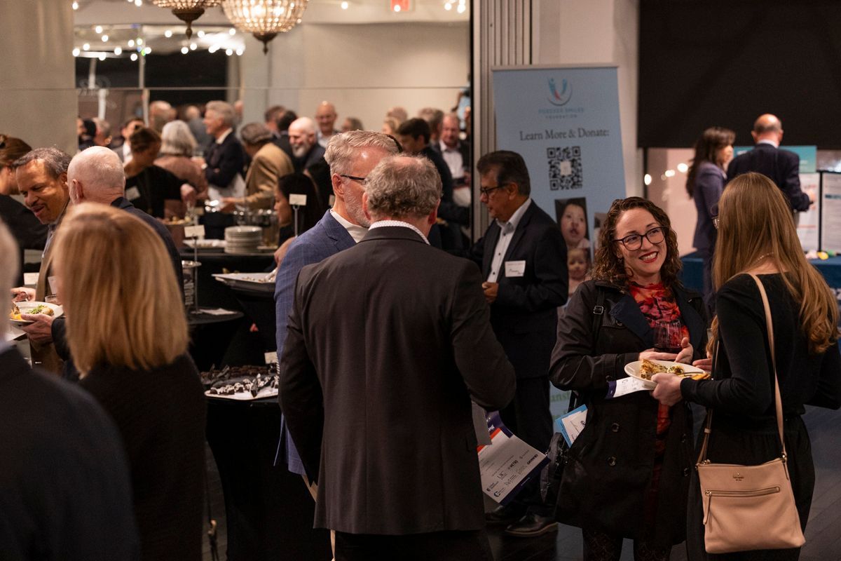 People at a networking event, talking and socializing. A few are holding snacks.