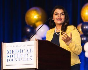 A woman is giving a speech at a podium for the medical society and foundation.
