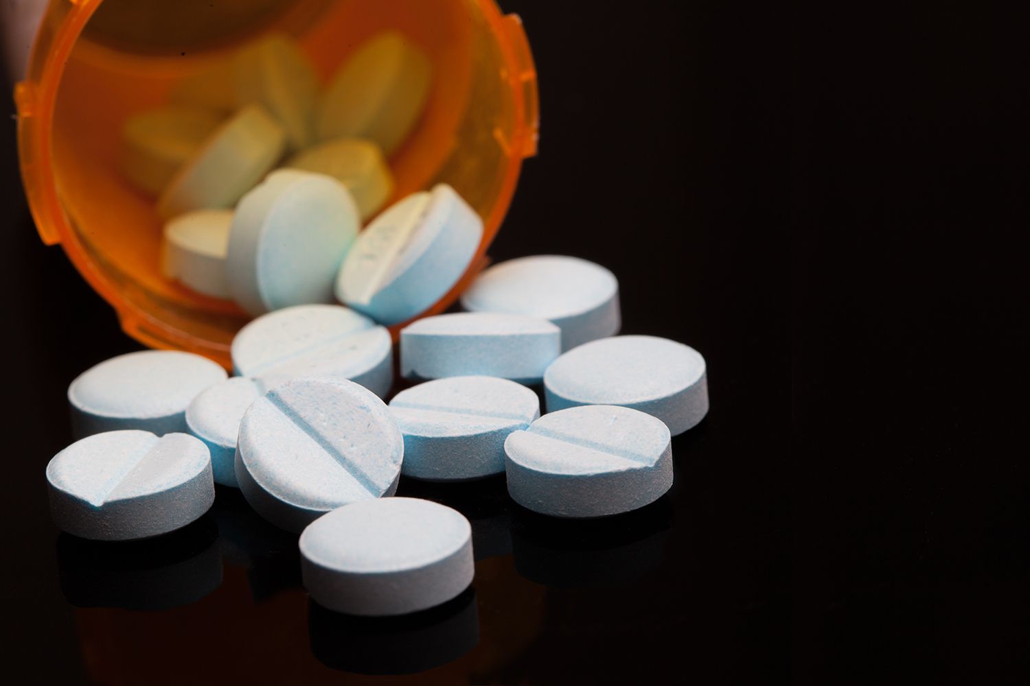 A bottle of pills is spilling out onto a table.