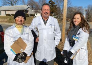A man and two women in white coats are standing next to each other.