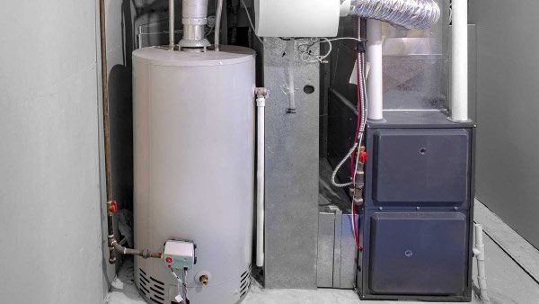 Water heater, furnace, and related components in a utility room. Gray and silver appliances on a white background.
