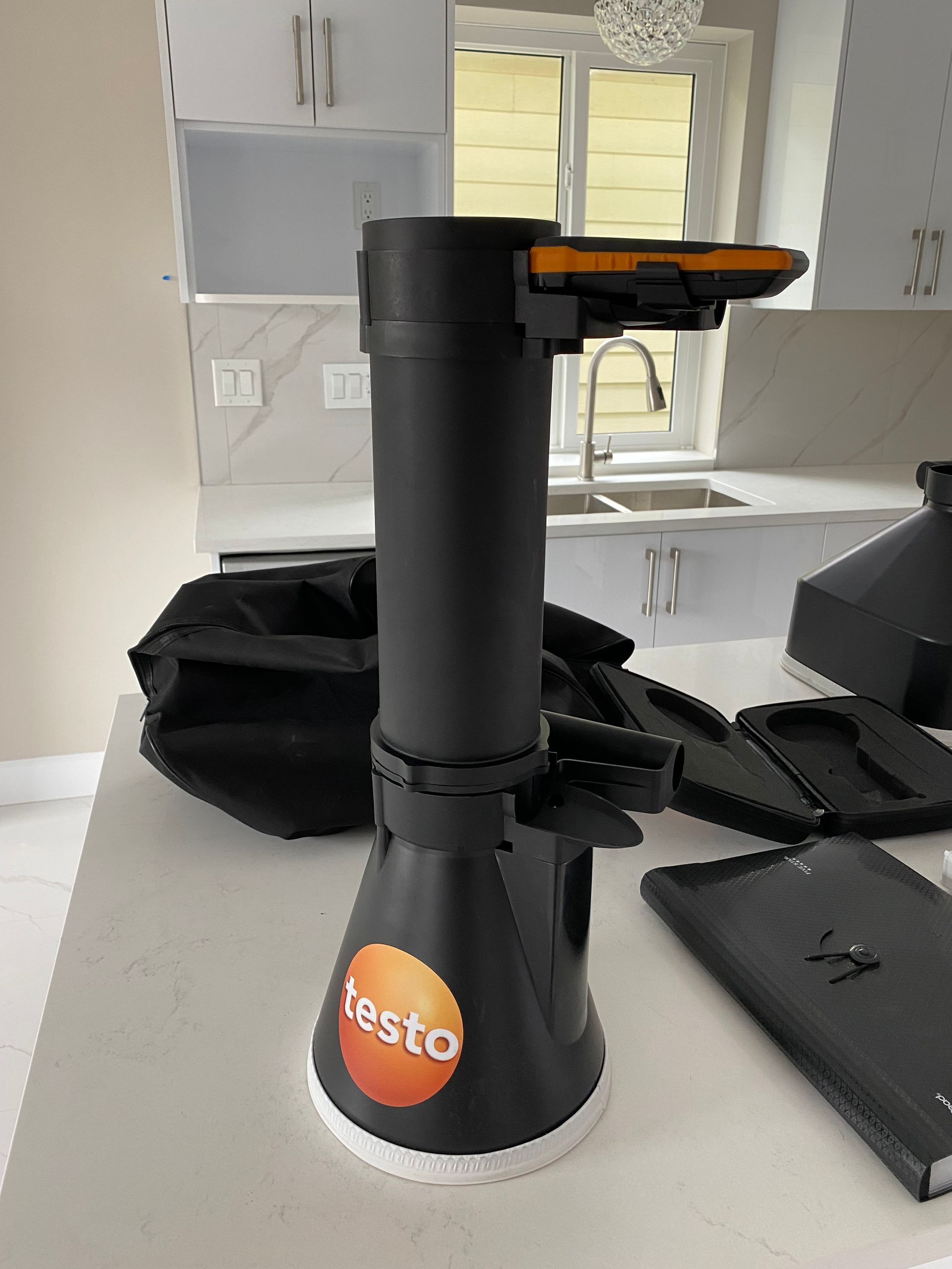 Black Testo combustion analyzer on a white countertop in a kitchen.