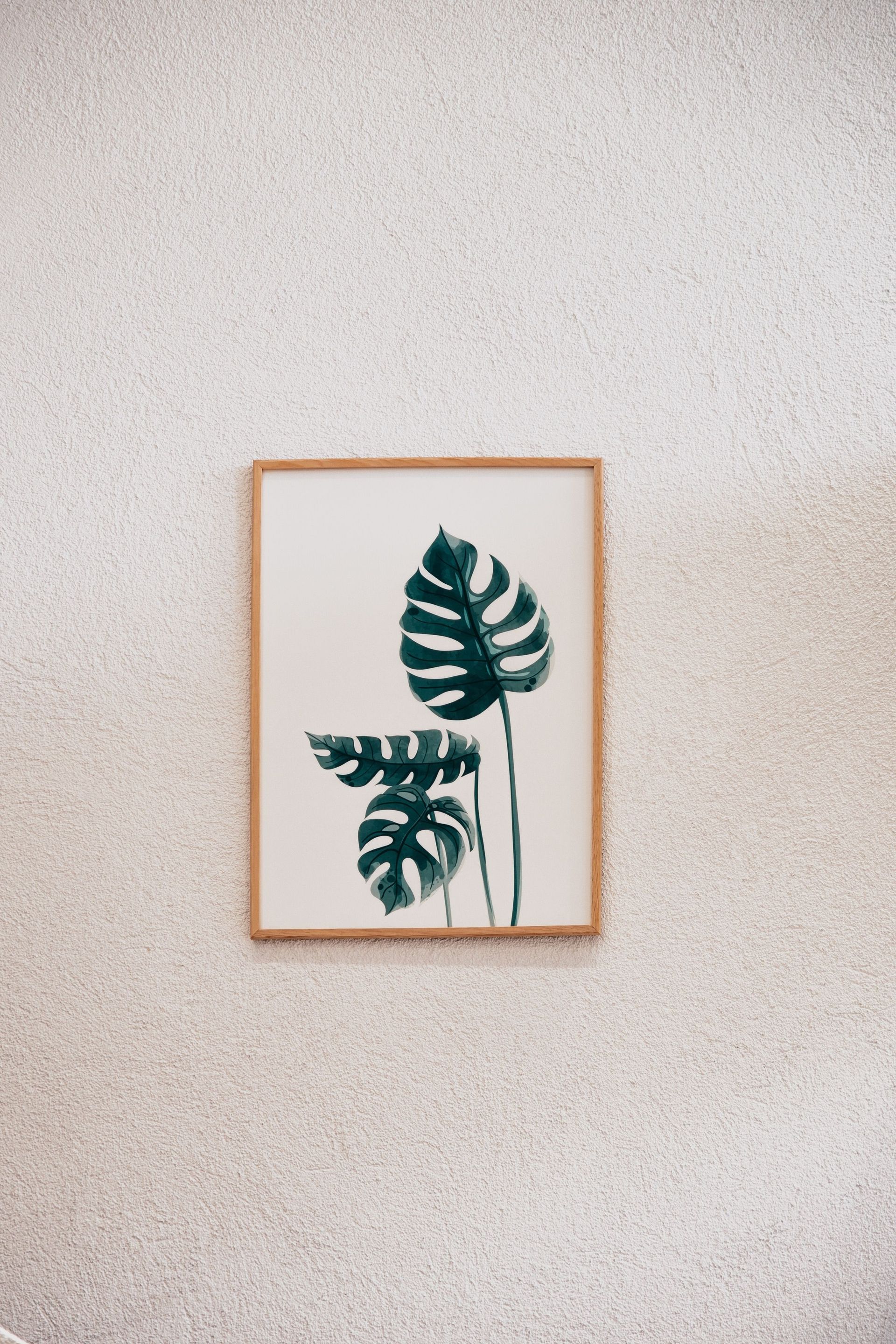 Framed botanical print with green leaves on a light speckled wall