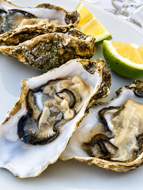 Ostriche aperte su un piatto con spicchi di limone e fette di lime.