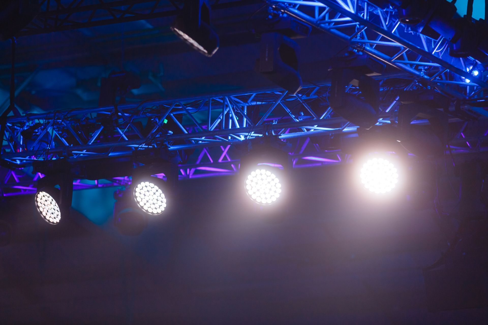 Blue stage truss with bright spotlights shining in a dark venue