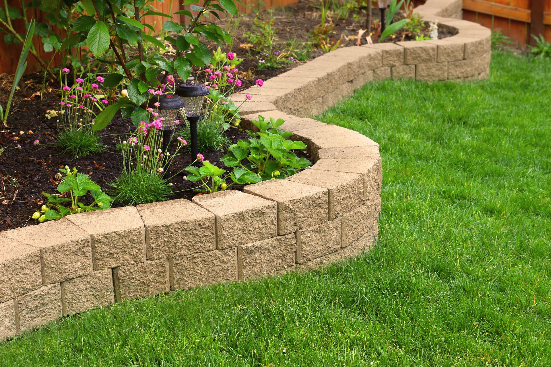Curved stone garden border edging a flower bed beside a green lawn