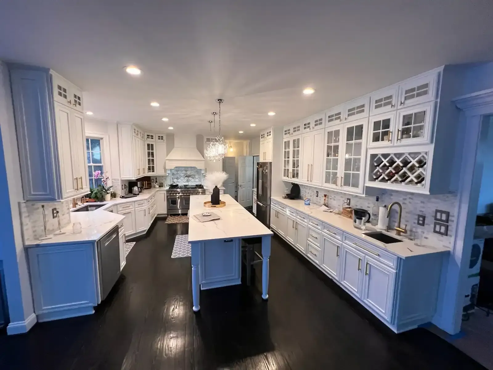 Bright blue and white kitchen with a large island, dark floor, and recessed ceiling lights.