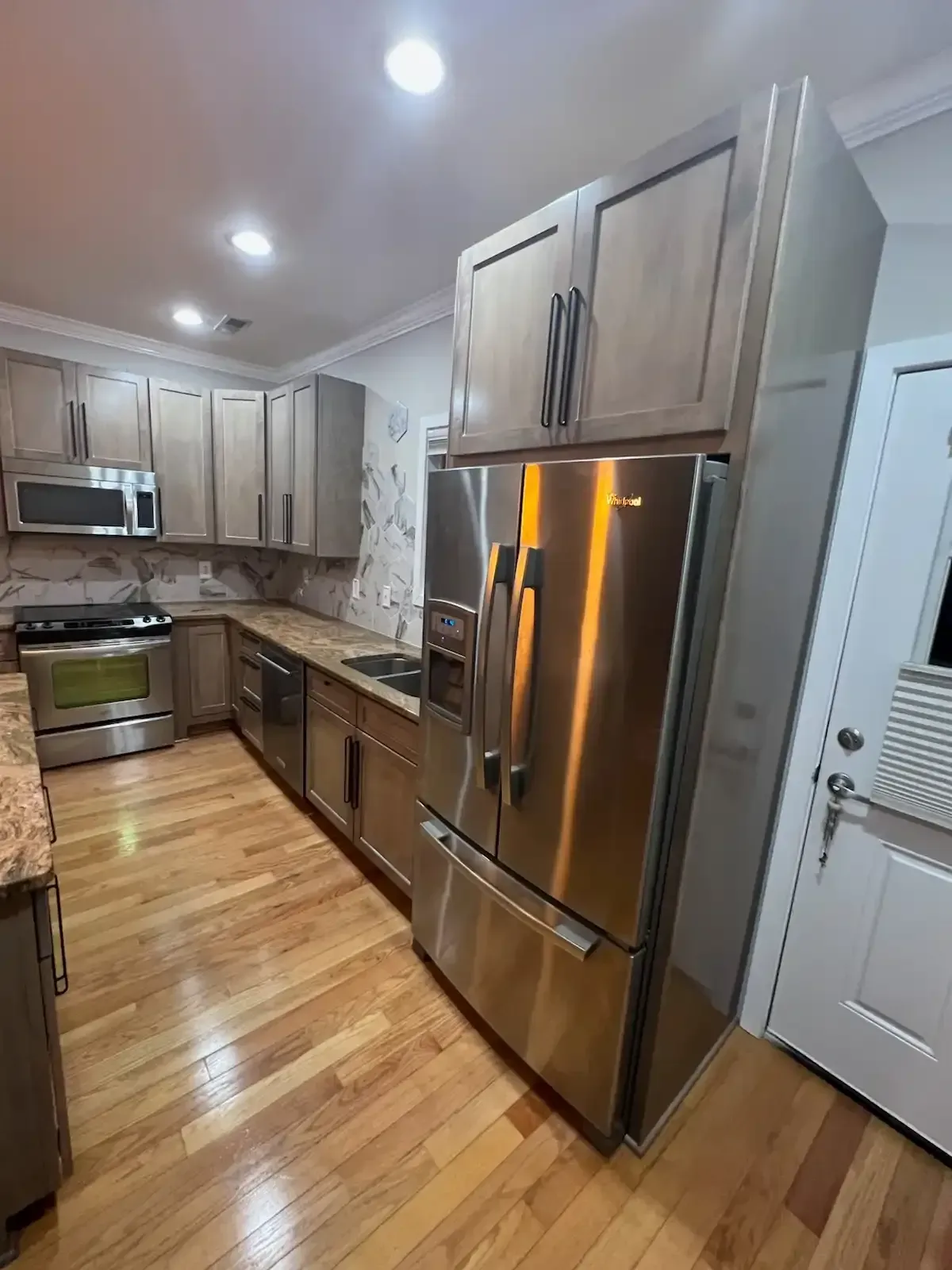 Modern kitchen with stainless steel appliances, wood cabinets, and hardwood floors