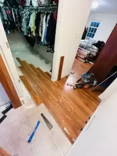 Damaged bedroom closet doorway with torn hardwood floor and tools on the ground