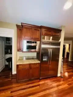 Kitchen with stainless steel refrigerator and built-in microwave, dark wood cabinets, and hardwood floors.