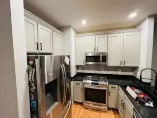 Bright kitchen with white cabinets, stainless steel appliances, and dark countertops