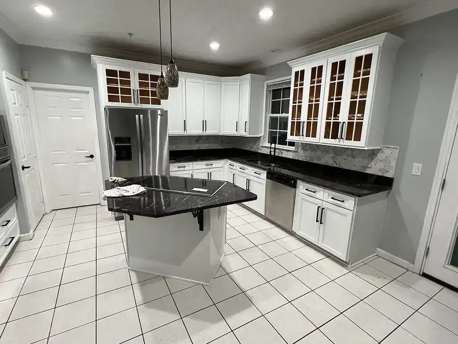 Modern kitchen with white cabinets, black granite countertops, stainless appliances, and a black island.
