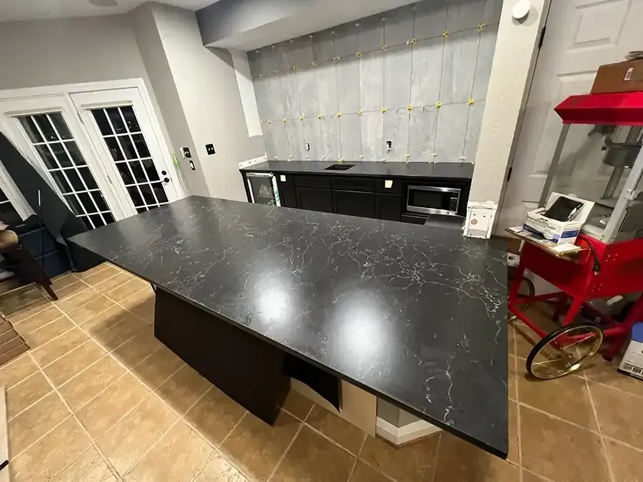 Modern kitchen with a large black island and tiled floor, viewed from above