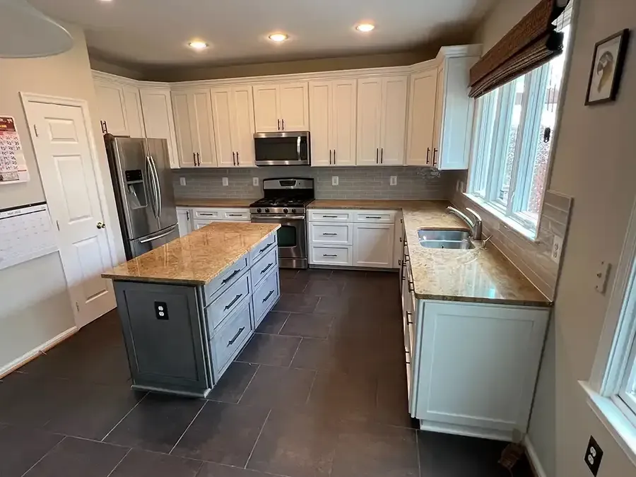 Modern kitchen with white cabinets, dark tile floor, stainless steel appliances, and a center island with wood countertops