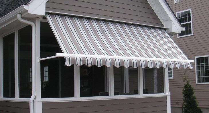 White striped awning extended over a house window and porch on a gray siding exterior