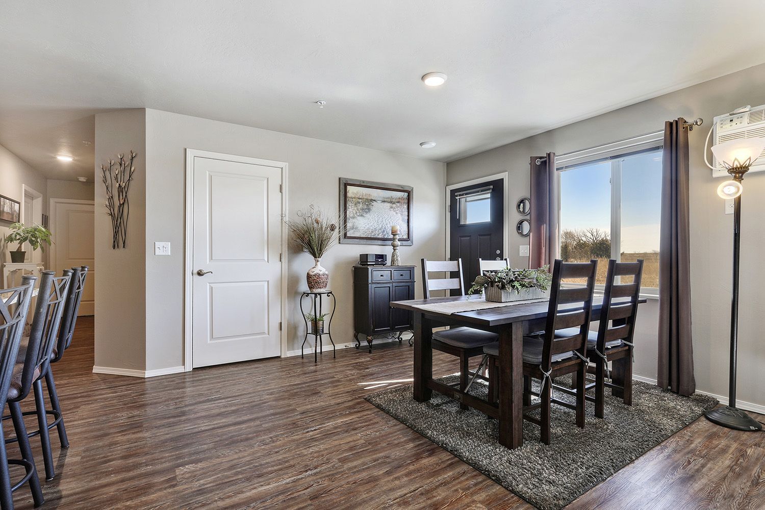 Dining room with dark wood table, chairs, and a lamp by large windows in a bright modern home.