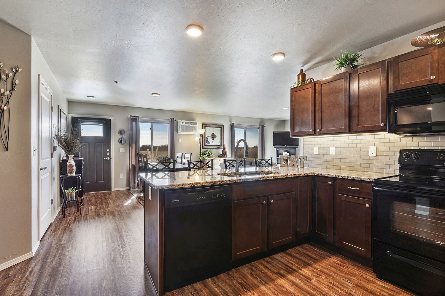 Modern kitchen with dark wood cabinets, black appliances, and a central island in a bright home interior