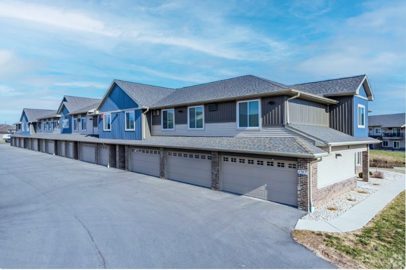 Row of modern gray townhouses with attached garages along a paved driveway