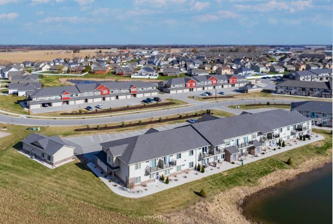 Aerial view of modern waterfront townhouses beside a canal with a larger neighborhood in the background
