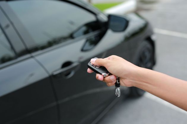 Person using a screwdriver to install a car stereo. Black dashboard and gray clothing are visible.
