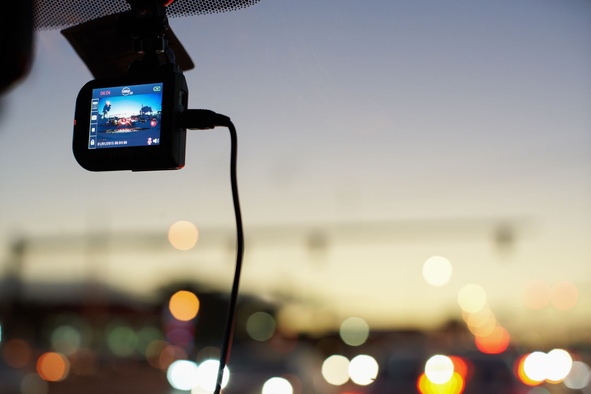 Dashcam recording a dusk cityscape through a windshield.