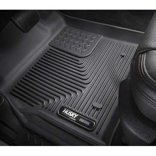 Black Husky Liners floor mat in a vehicle, with textured surfaces for grip.