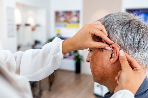 Doctor Fitting A Male Patient With A Hearing Aid — Belfast, ME — Hearing Solutions Doctor Fitting A Male Patient With A Hearing Aid — Belfast, ME — Hearing Solutions