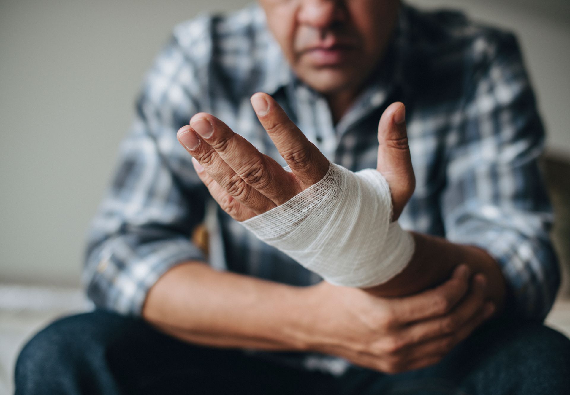A man with a bandaged hand is sitting on a bed.