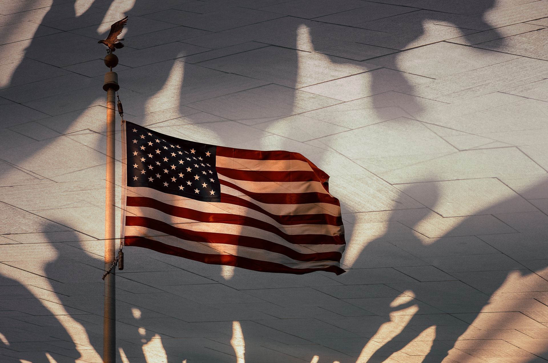 An American flag is flying in the wind on a pole
