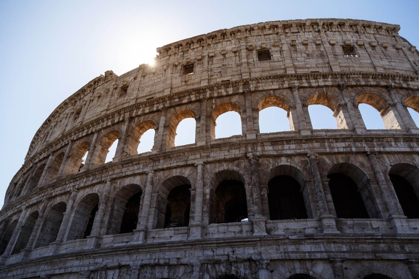 El sol brilla a través de los arcos del Coliseo de Roma.