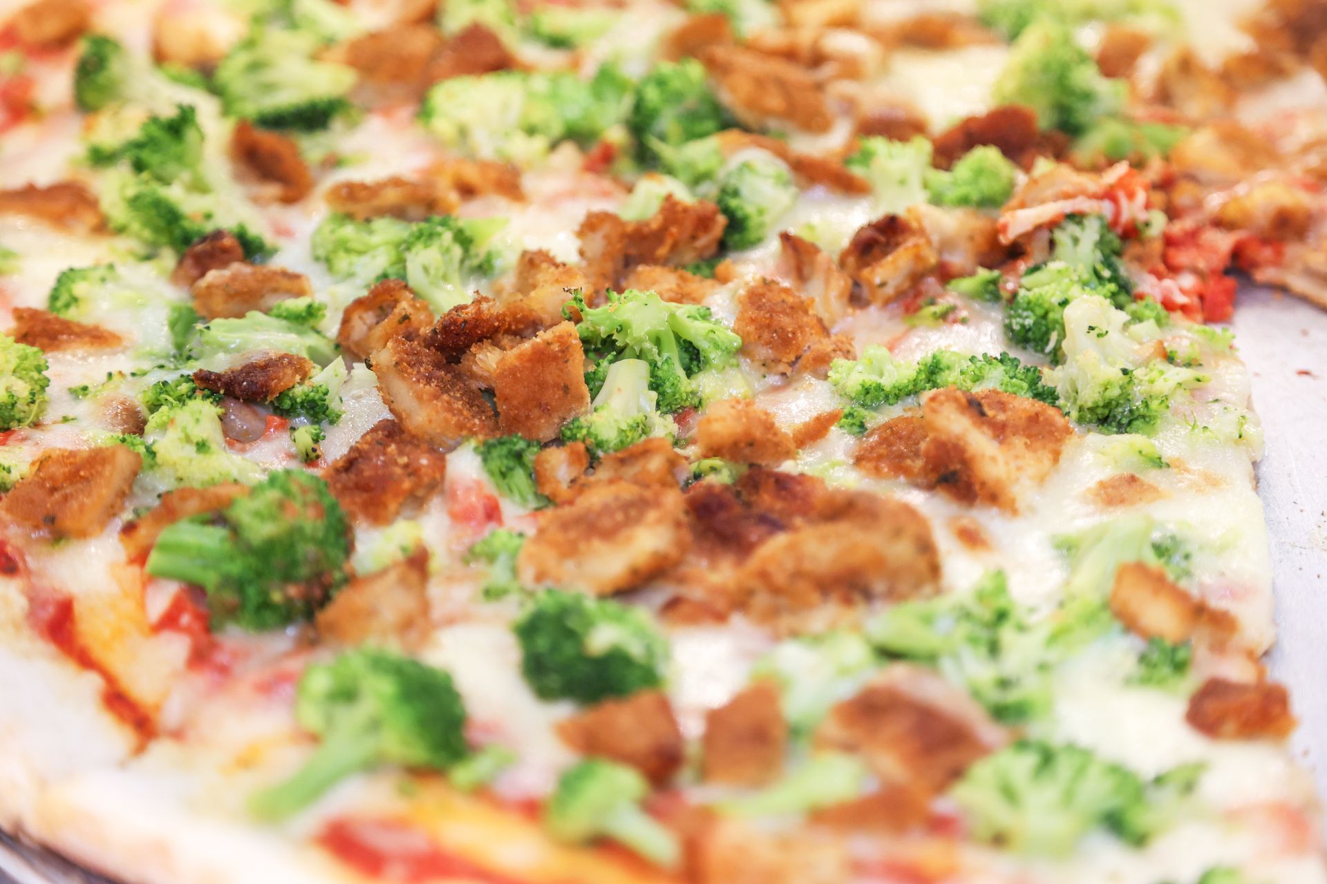 Close-up of pizza with melted cheese, broccoli, and browned toppings