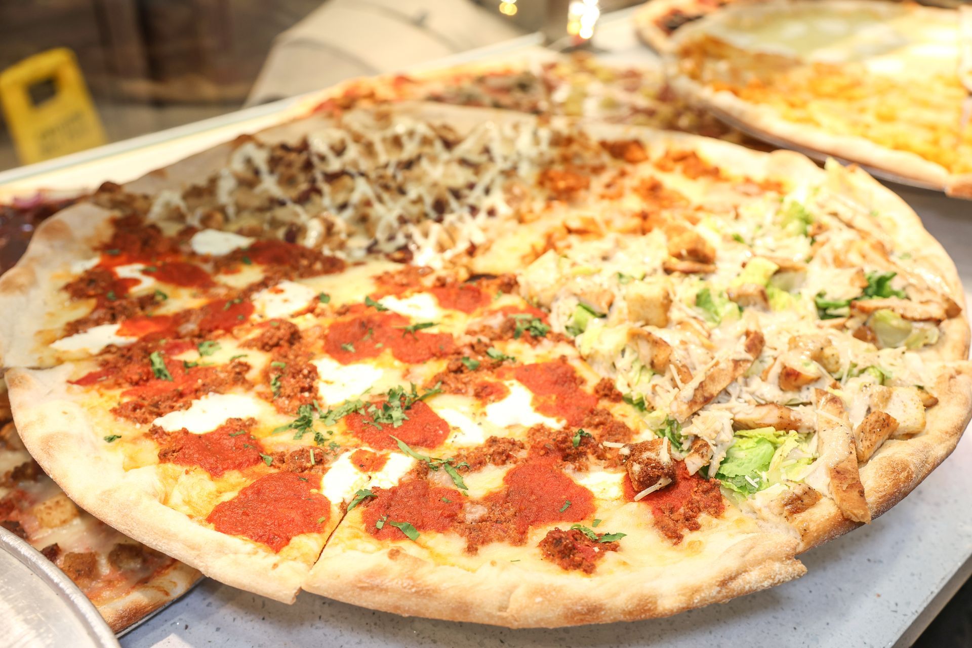 Large pizza on a tray with red sauce, cheese, and toppings cut into slices