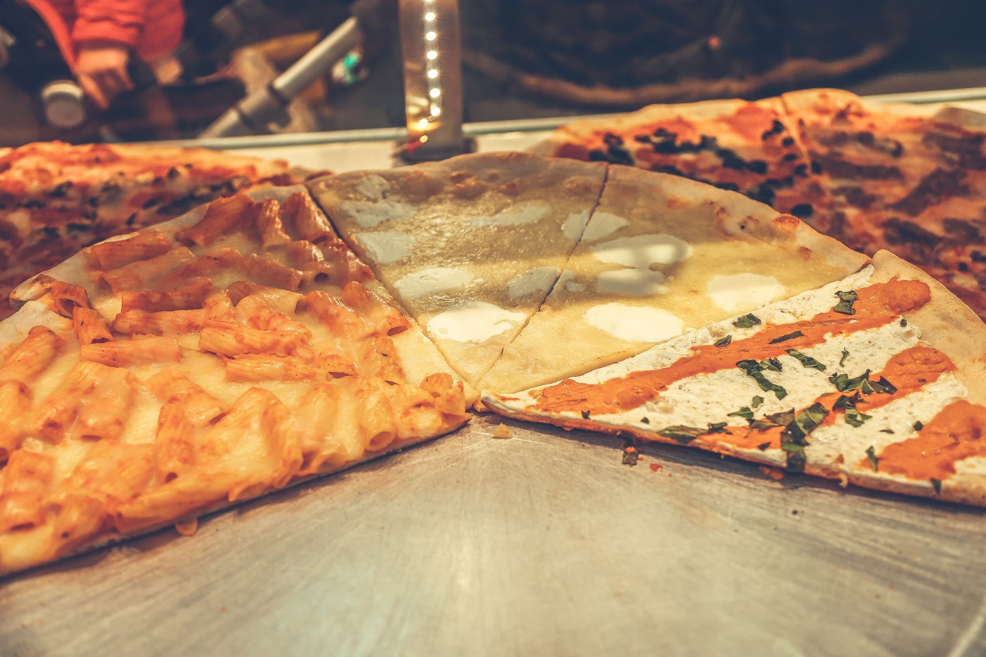 Assorted pizza slices on a tray at a restaurant counter