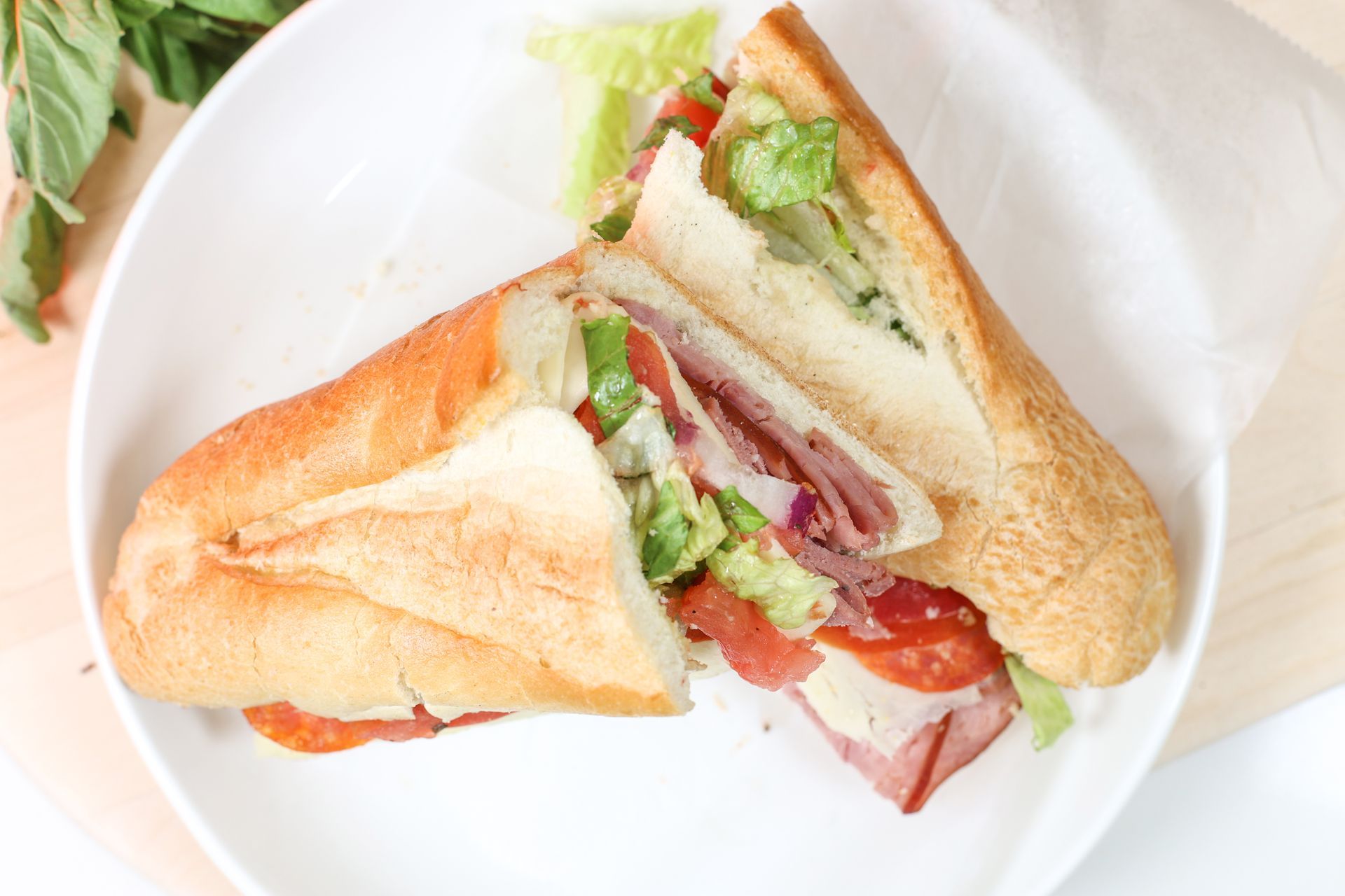 Sandwich with lettuce and tomato on a white plate, cut in half