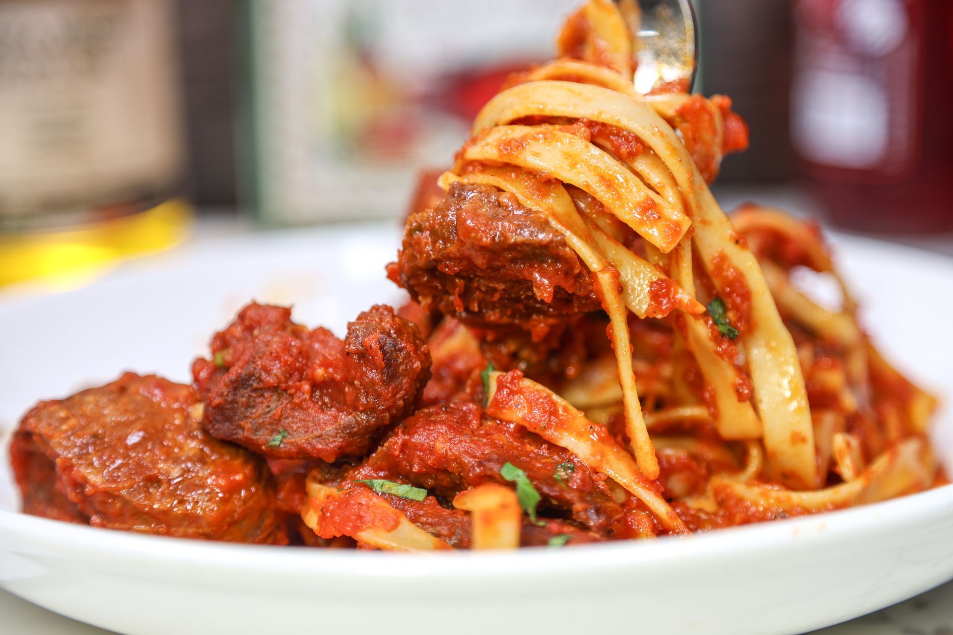 Plate of spaghetti in red meat sauce with meatballs, garnished with herbs.