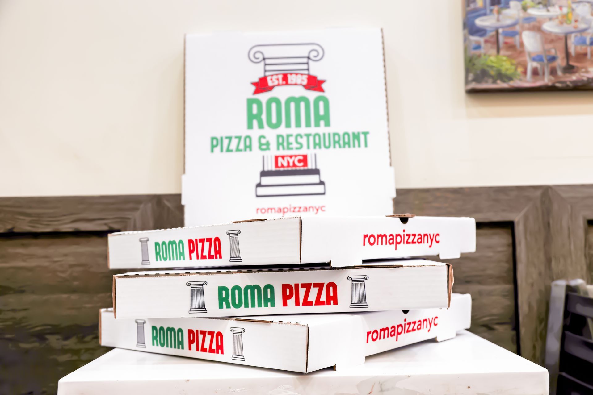 Stacks of white Roma Pizza boxes on a table in a restaurant setting