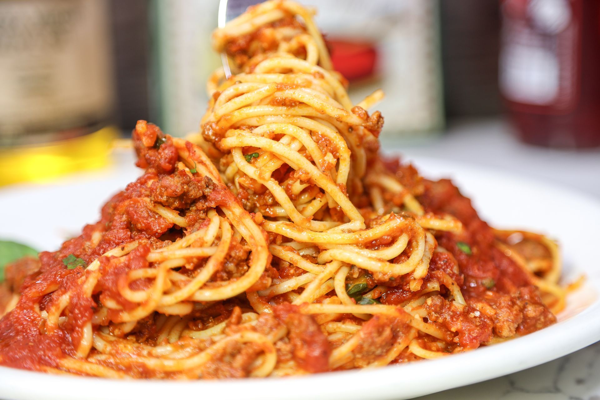 Plate of spaghetti with red tomato sauce and herbs on a table
