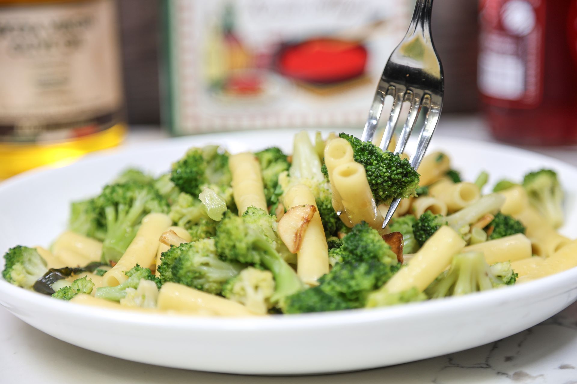 Plate of broccoli and pasta with a fork in a close-up kitchen setting