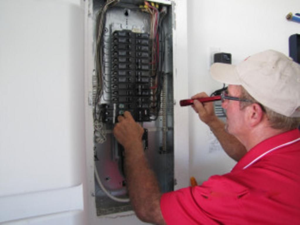 A man in a red shirt is working on an electrical box