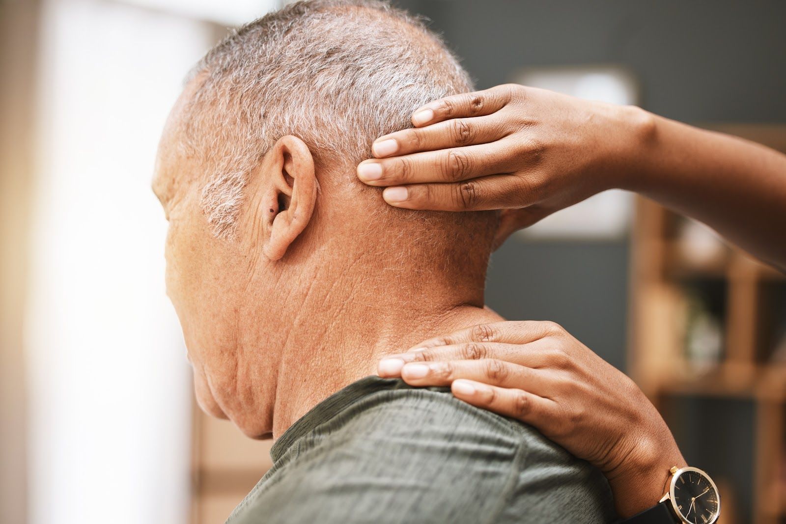 Hands massaging the back of a man's neck and shoulder in a close-up scene