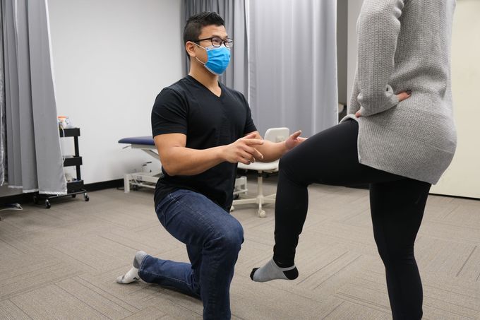A man wearing a mask is kneeling down next to a woman.