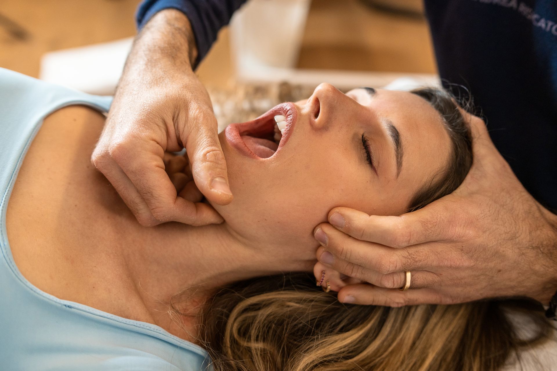 A woman is laying on a table getting a massage from a man.